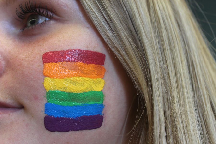 Junior Maggie Miller supporting the LGBTQ+ community by previewing the Pride flag on her cheek.
