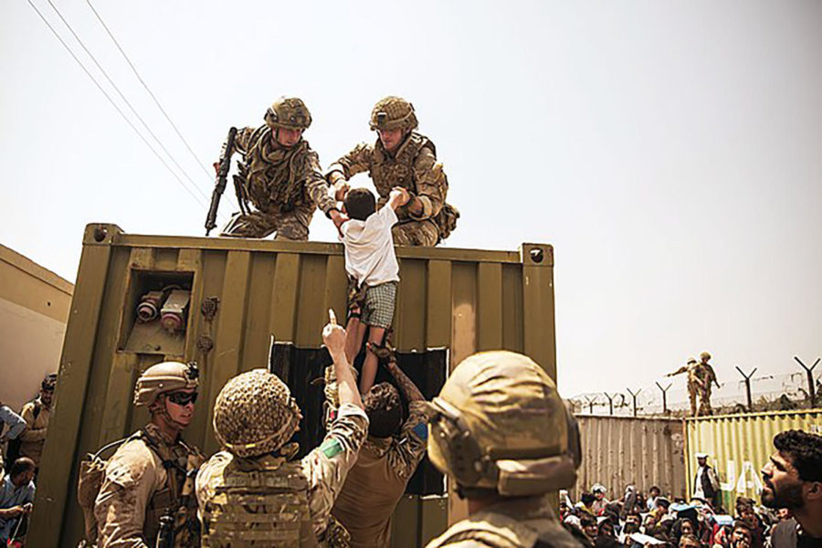American soldiers help lift a young Afghan boy on to a military vehicle amid the Kabul evacuations. Photo courtesy of Wikimedia. 