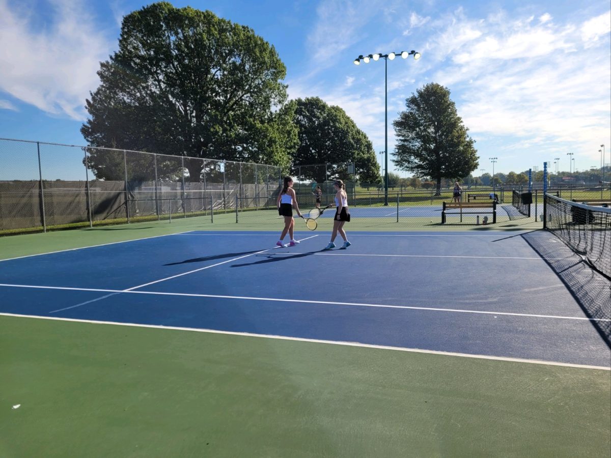 Brotherton and Martin tap tennis rackets after a point in a match. 