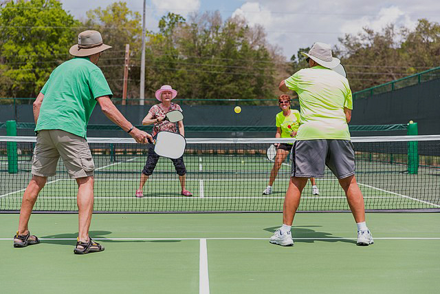 Senior Citizens enjoying a doubles match of pickleball. 