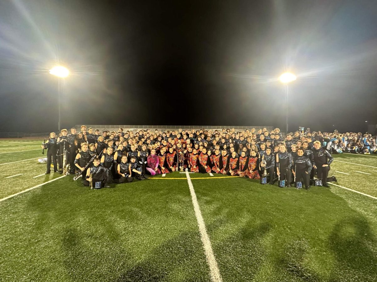 The Kickapoo Golden Arrow Band participates in a celebratory group photo after a successful competition day during the Fall 2023 Marching season.