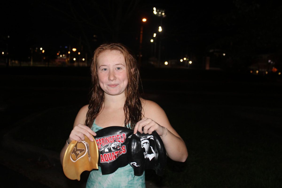 Morgan showing her journey and growth as a swimmer with her old and current swim caps. 